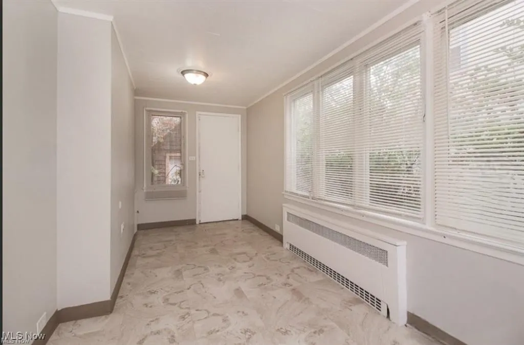 Corridor with radiator heating unit, crown molding, and baseboards