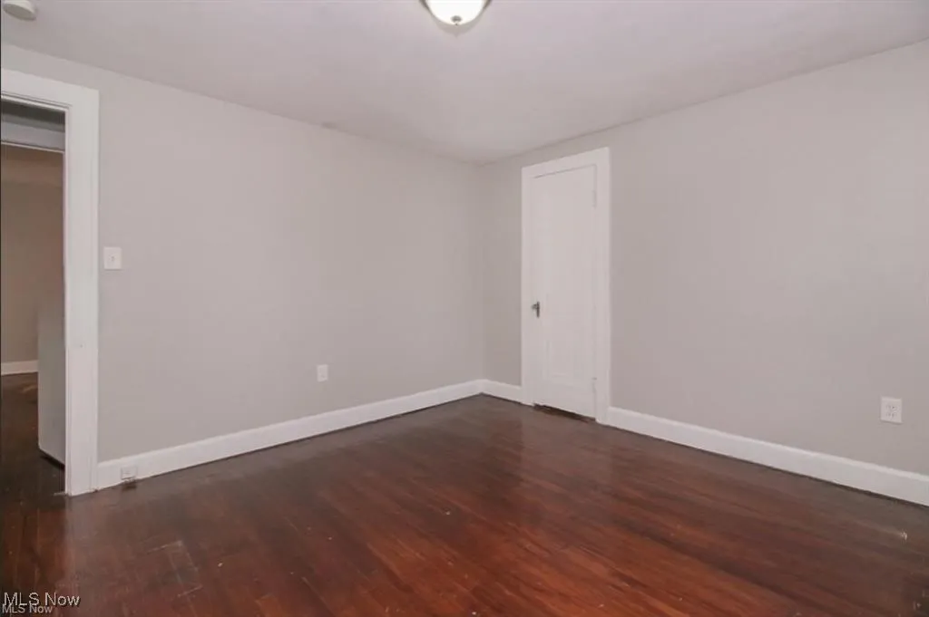 Unfurnished room featuring baseboards and dark wood finished floors