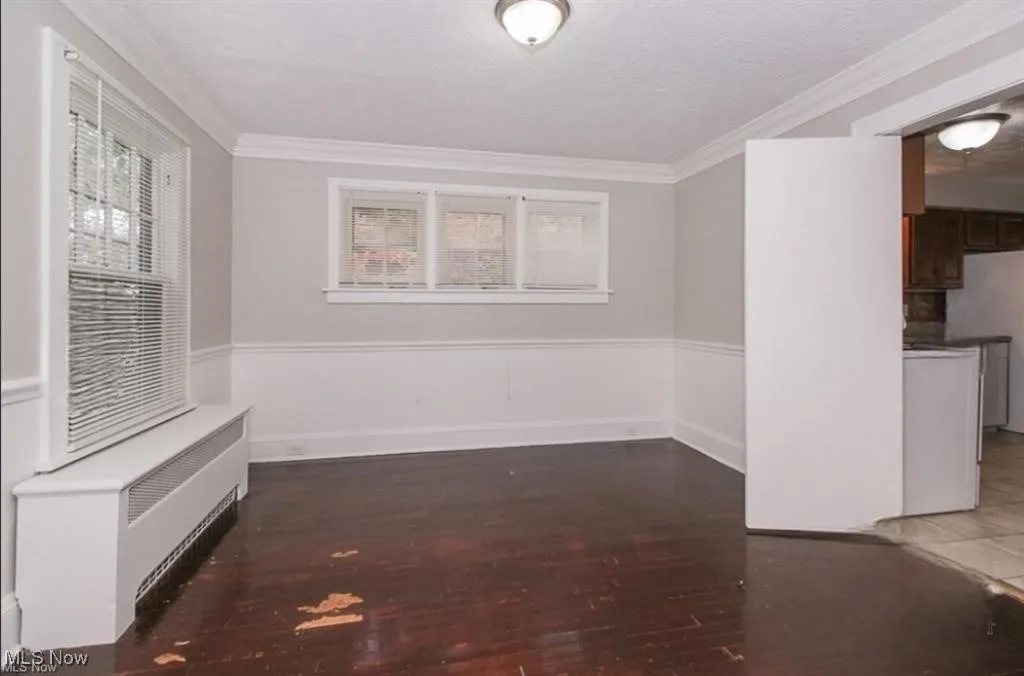 Spare room featuring a wealth of natural light, crown molding, a textured ceiling, and wood finished floors