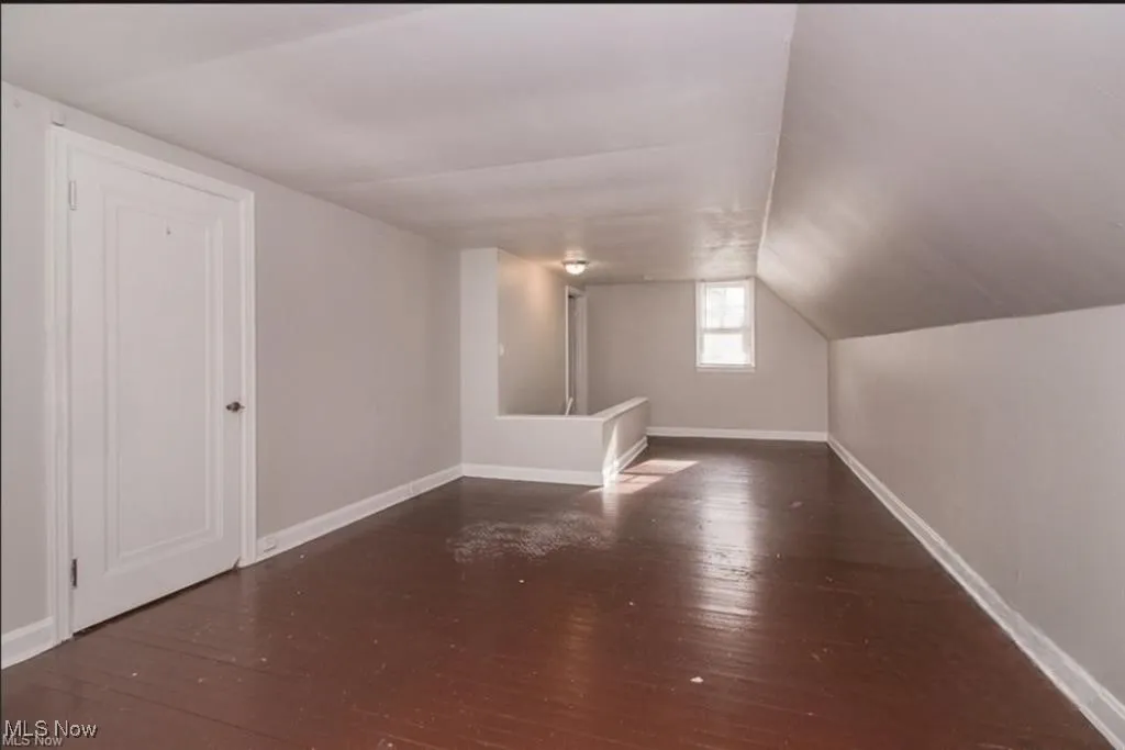 Additional living space featuring hardwood / wood-style floors, baseboards, and vaulted ceiling