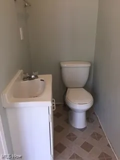 Bathroom featuring toilet, vanity, and baseboards