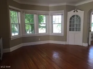 Unfurnished dining area featuring baseboards, crown molding, and wood finished floors