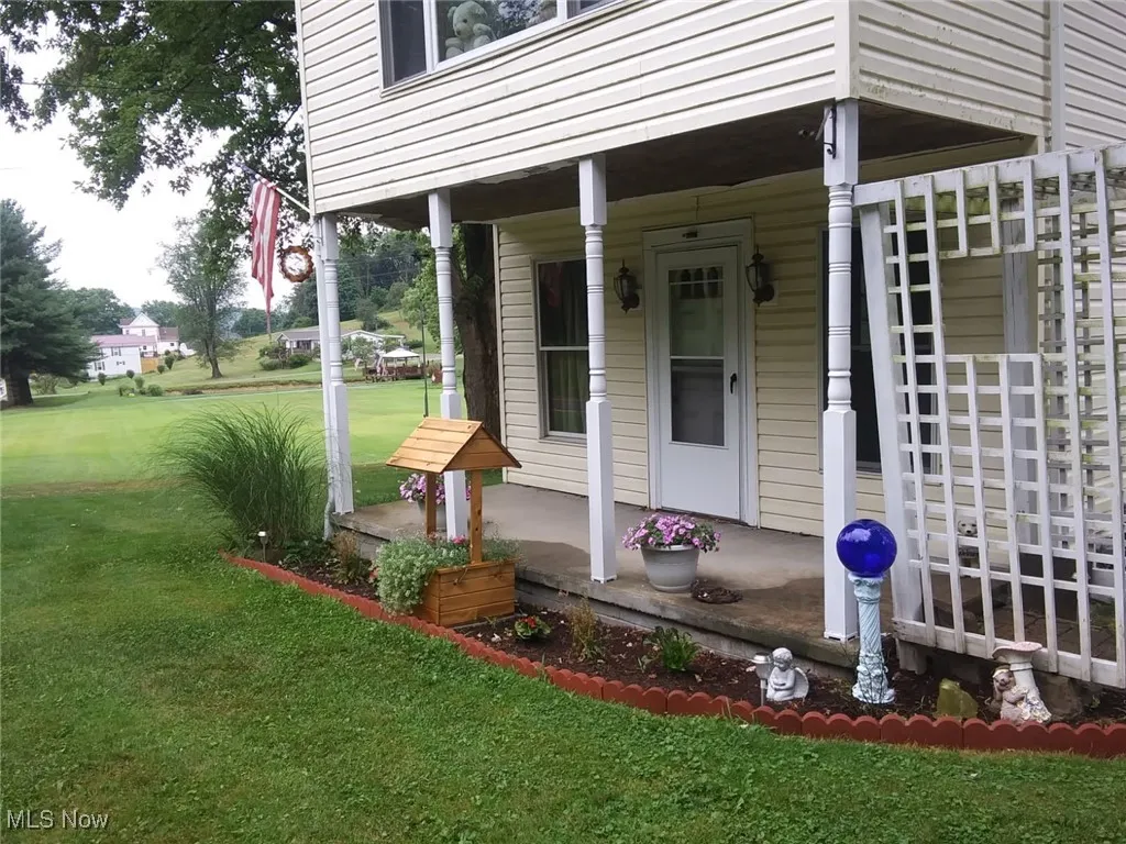 Doorway to property featuring a lawn and a porch