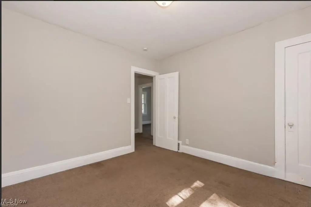 Carpeted empty room with baseboards