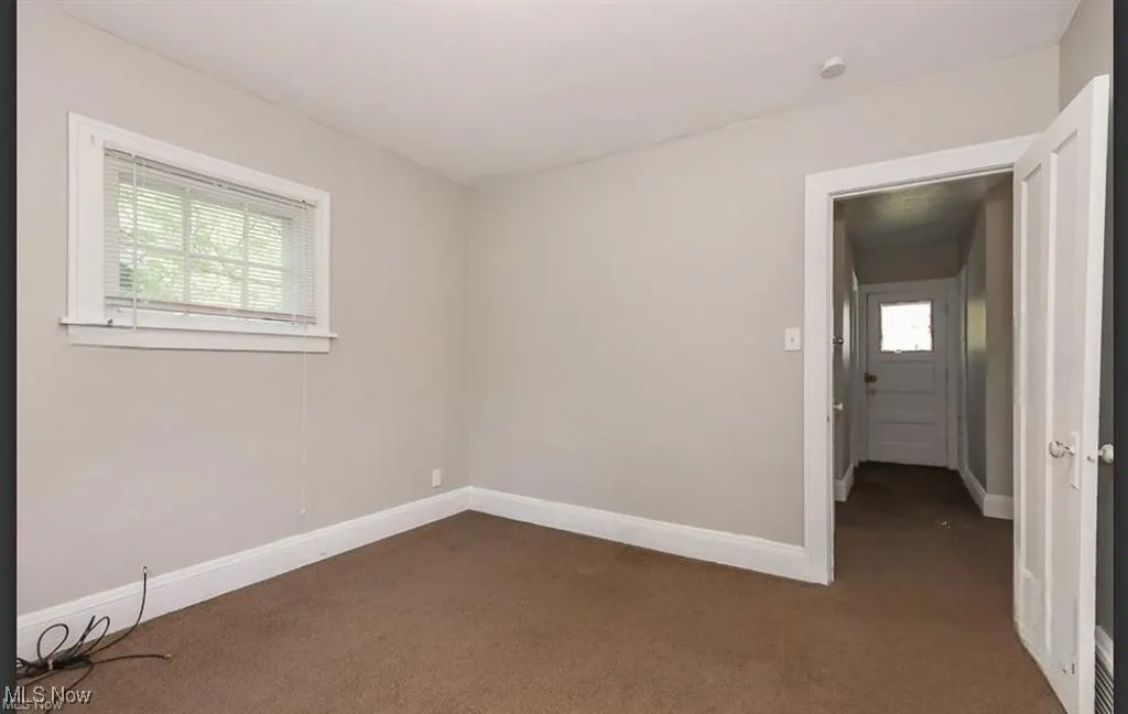 Spare room featuring baseboards and dark colored carpet