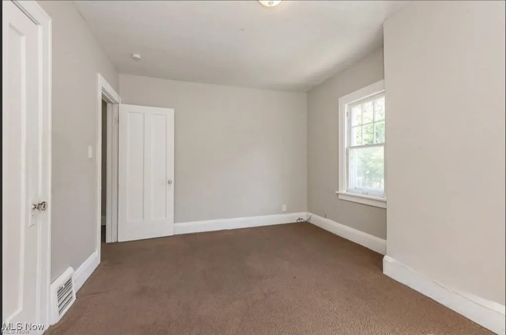 Unfurnished bedroom featuring baseboards, visible vents, and dark carpet