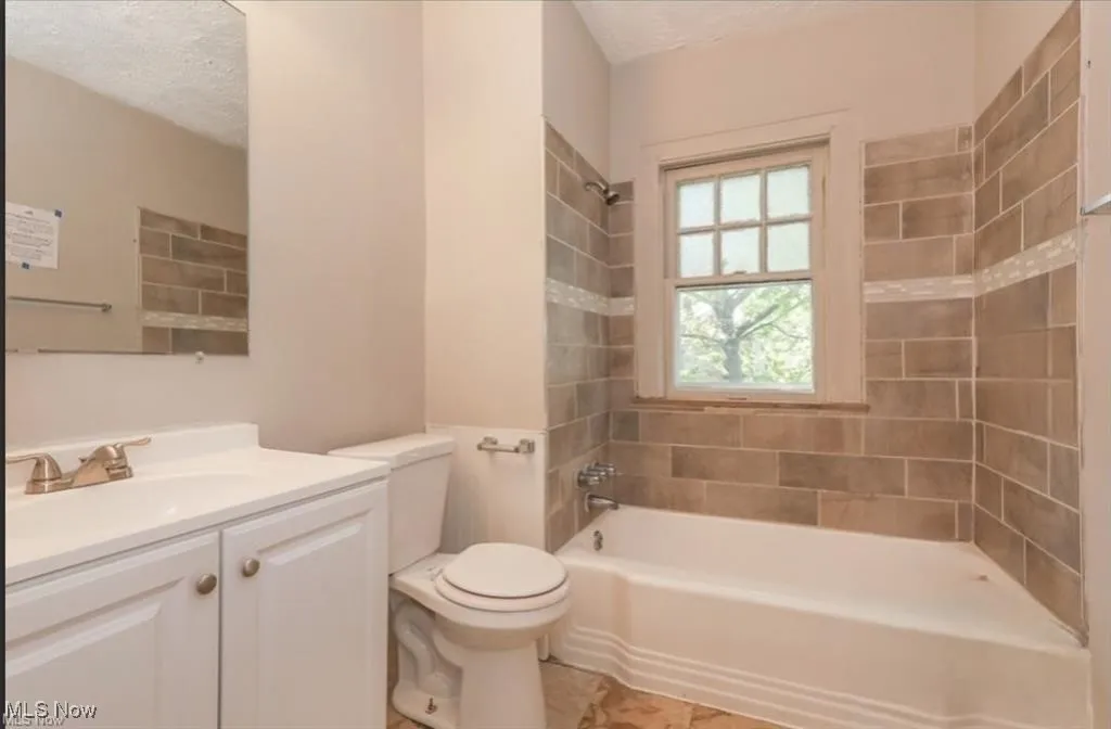 Full bath with toilet, vanity, shower / bathtub combination, and a textured ceiling