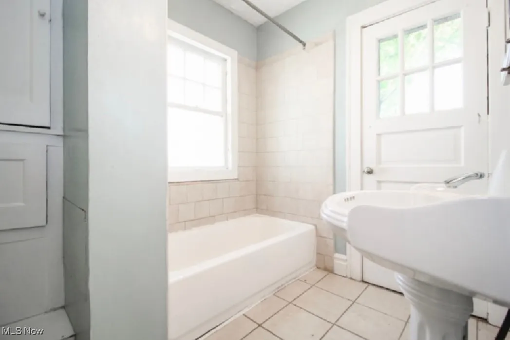 Full bath featuring a wealth of natural light, a sink, tile patterned flooring, and shower / bathtub combination