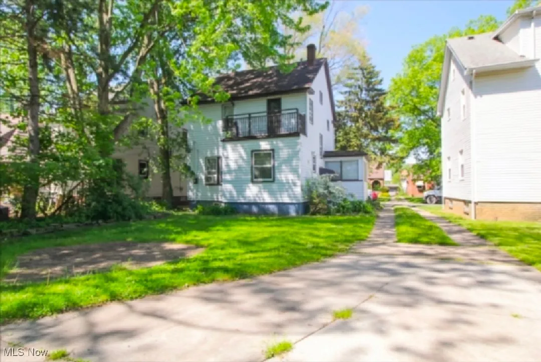 View of side of property featuring a balcony, a chimney, and a yard