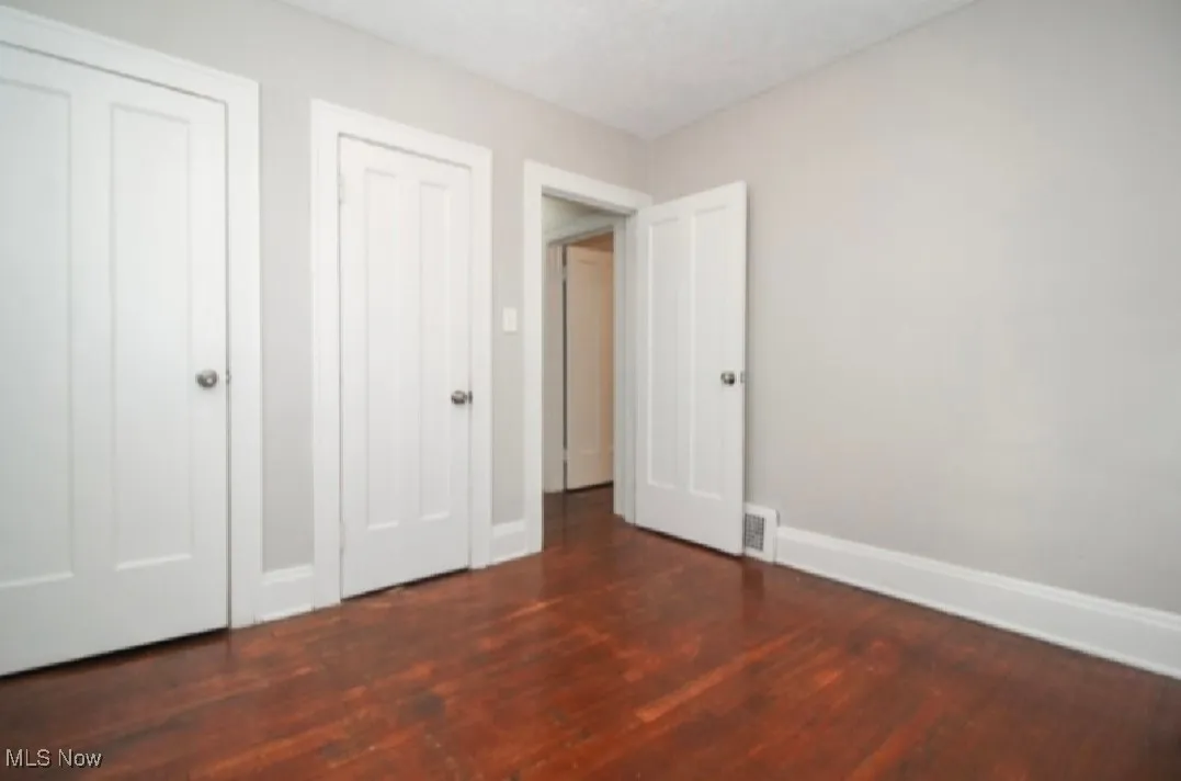 Unfurnished bedroom with baseboards, visible vents, and wood finished floors