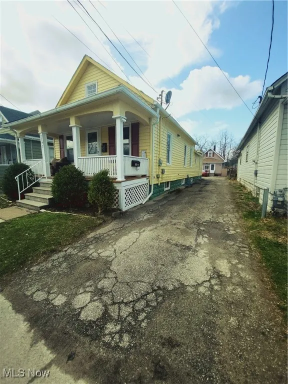 Shotgun-style home featuring aphalt driveway and covered porch