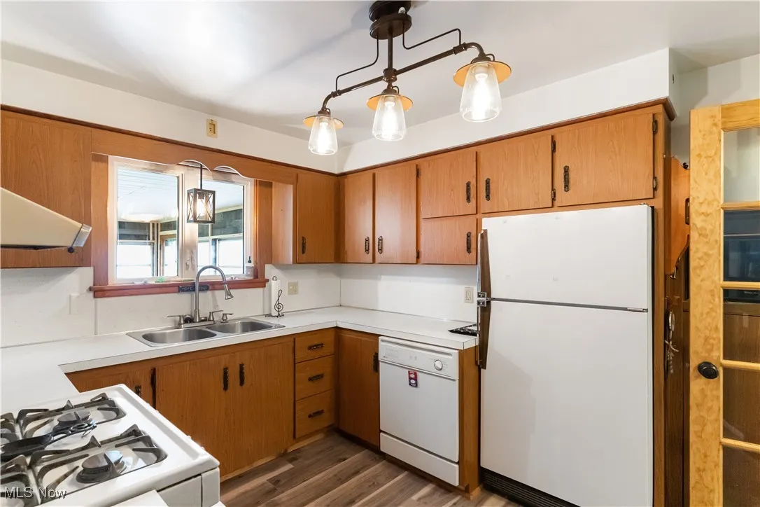 Kitchen with dark wood-style floors, light countertops, a sink, and white appliances