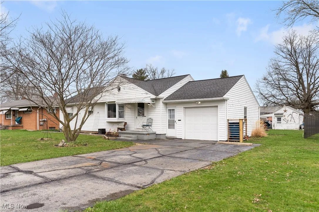View of front of home with driveway, a front lawn, roof with shingles, and an attached garage