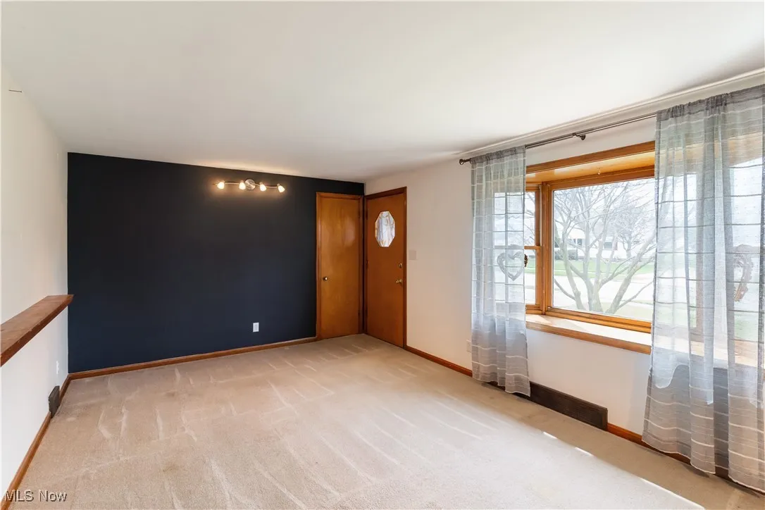 Empty room with light colored carpet and baseboards