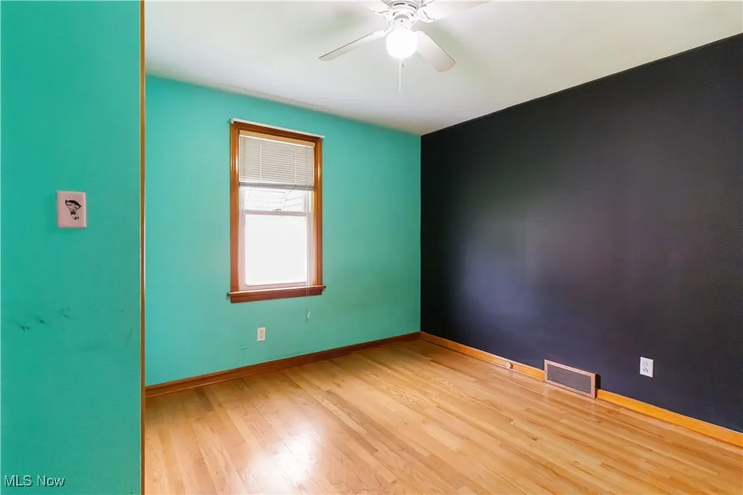 Empty room with baseboards, visible vents, a ceiling fan, and wood finished floors