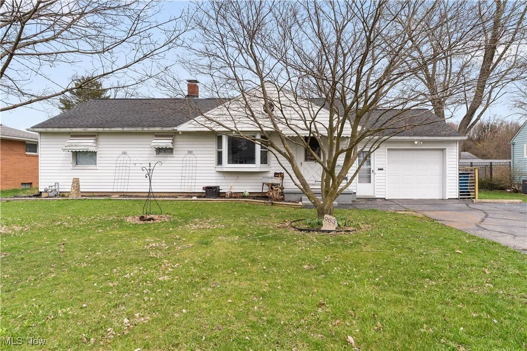 Single story home with central AC unit, a chimney, a front yard, driveway, and a shingled roof