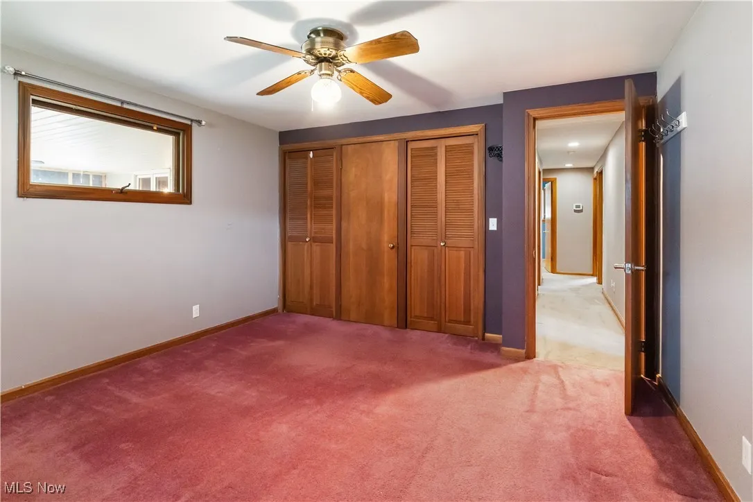 Unfurnished bedroom with baseboards, a closet, carpet, and a ceiling fan