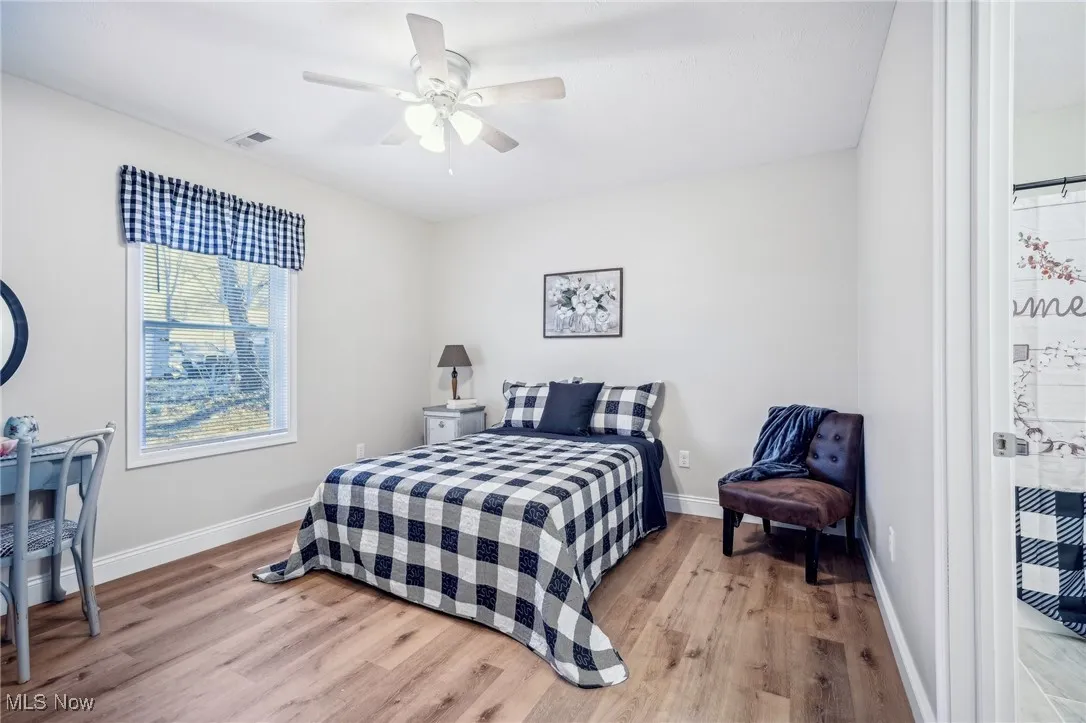 Bedroom featuring a ceiling fan, wood finished floors, visible vents, and baseboards