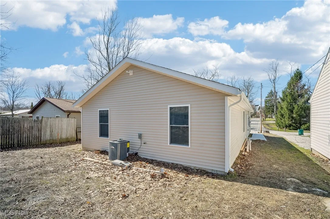 Rear view of property featuring fence and central AC
