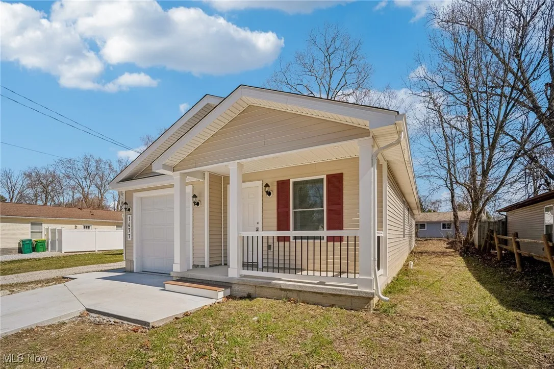 View of front facade with fence, a porch, concrete driveway, a front yard, and an attached garage