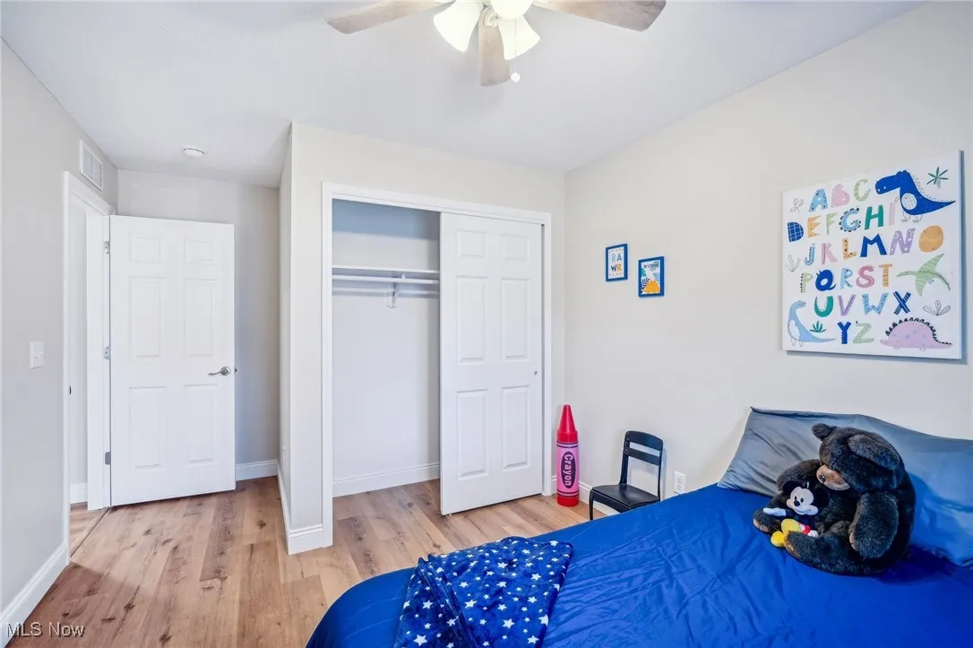 Bedroom with visible vents, baseboards, wood finished floors, a closet, and a ceiling fan