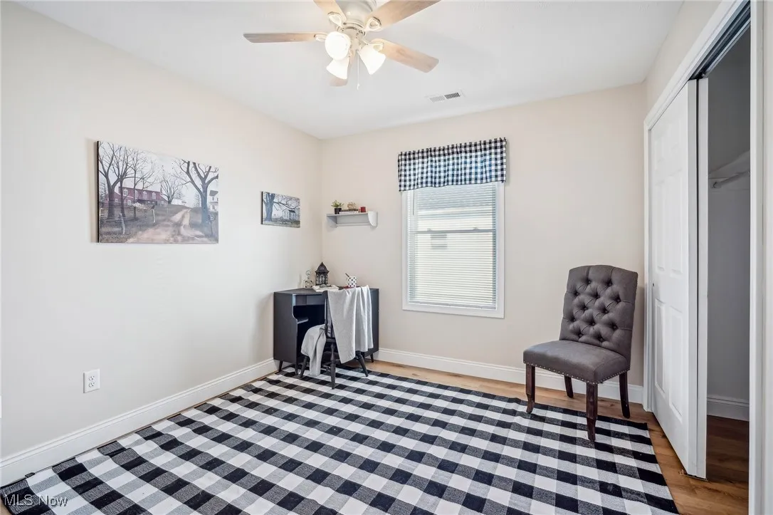 Living area with visible vents, a ceiling fan, light wood-type flooring, and baseboards
