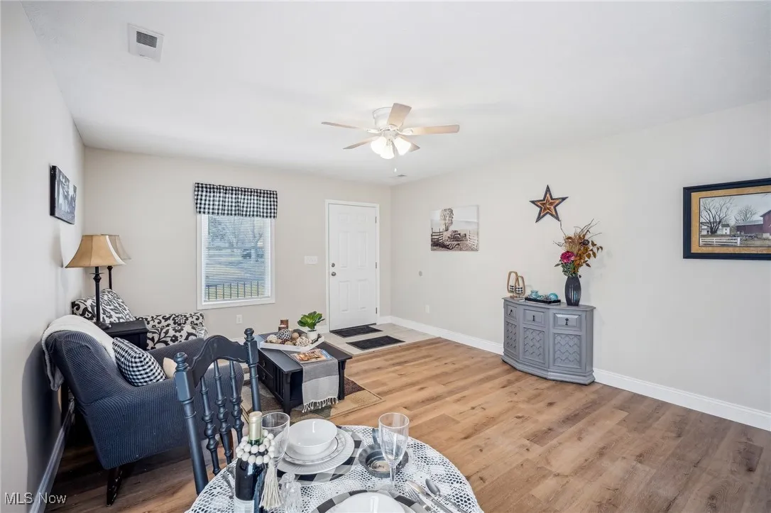Living room featuring baseboards, wood finished floors, visible vents, and ceiling fan