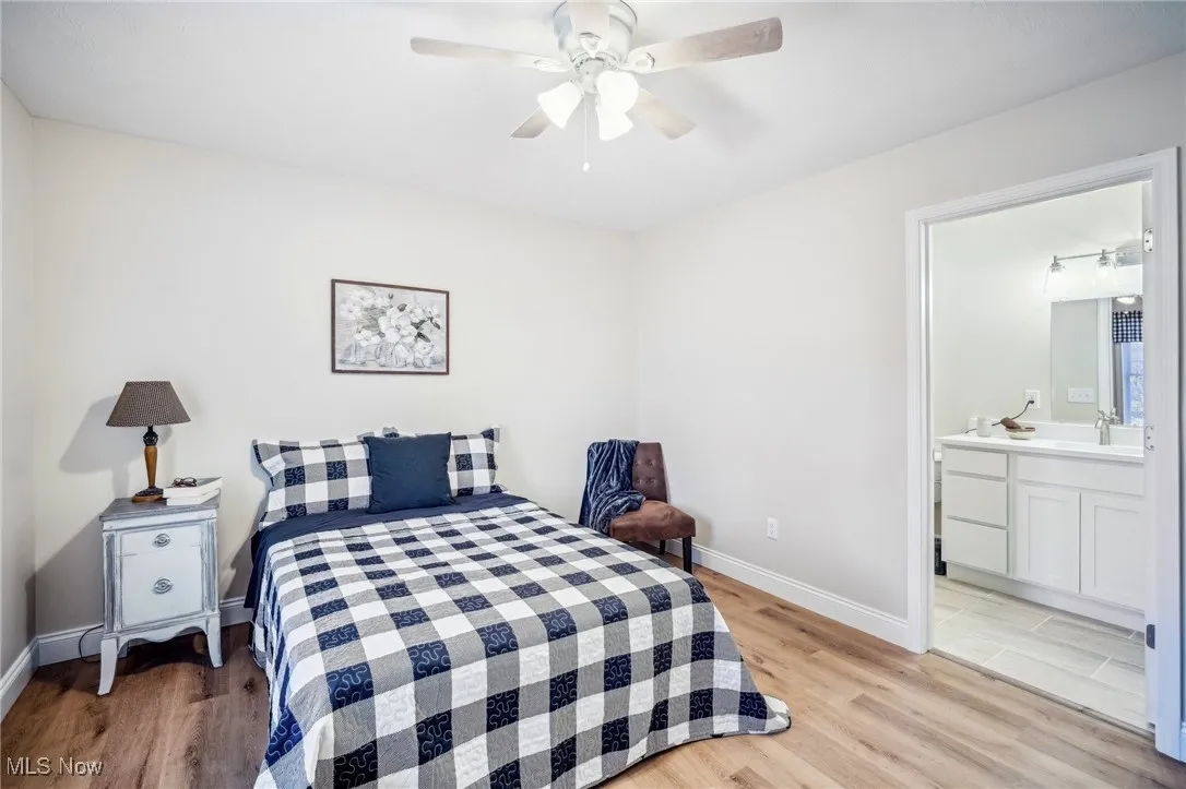 Bedroom featuring light wood-style floors, baseboards, ensuite bathroom, and a sink