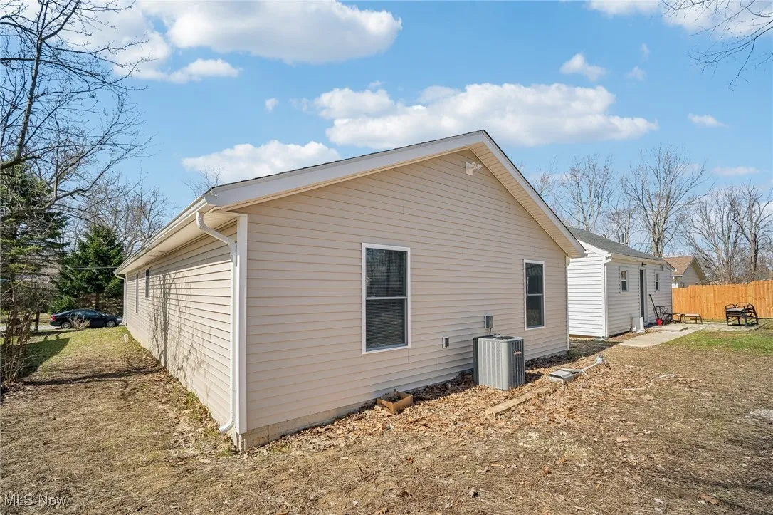 View of side of property featuring fence and central AC