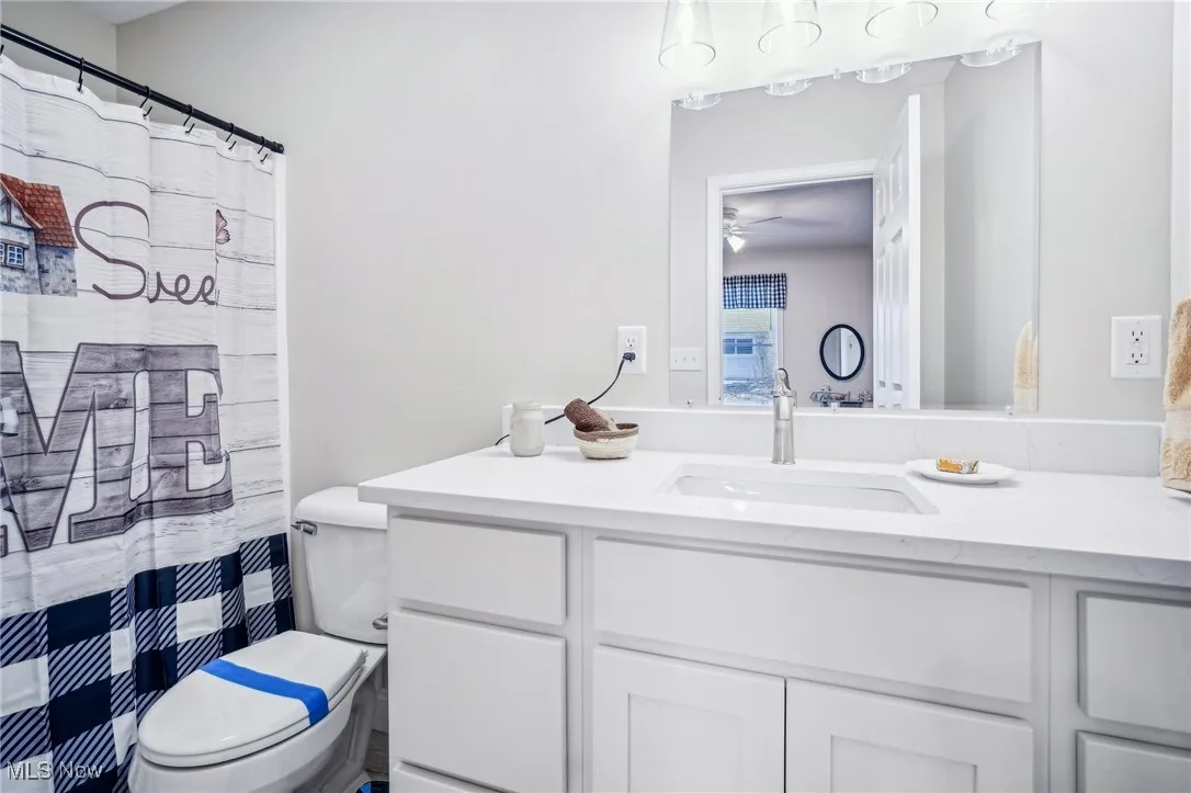 Full bath with vanity, toilet, and a ceiling fan