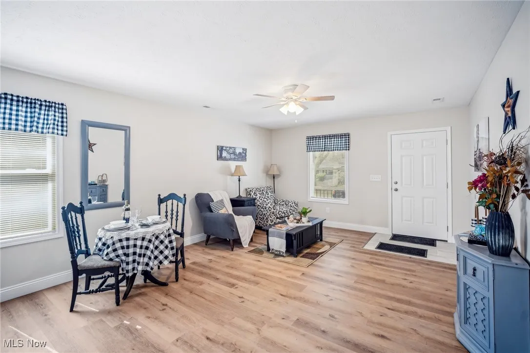 Living area featuring light wood-style flooring, baseboards, and a ceiling fan