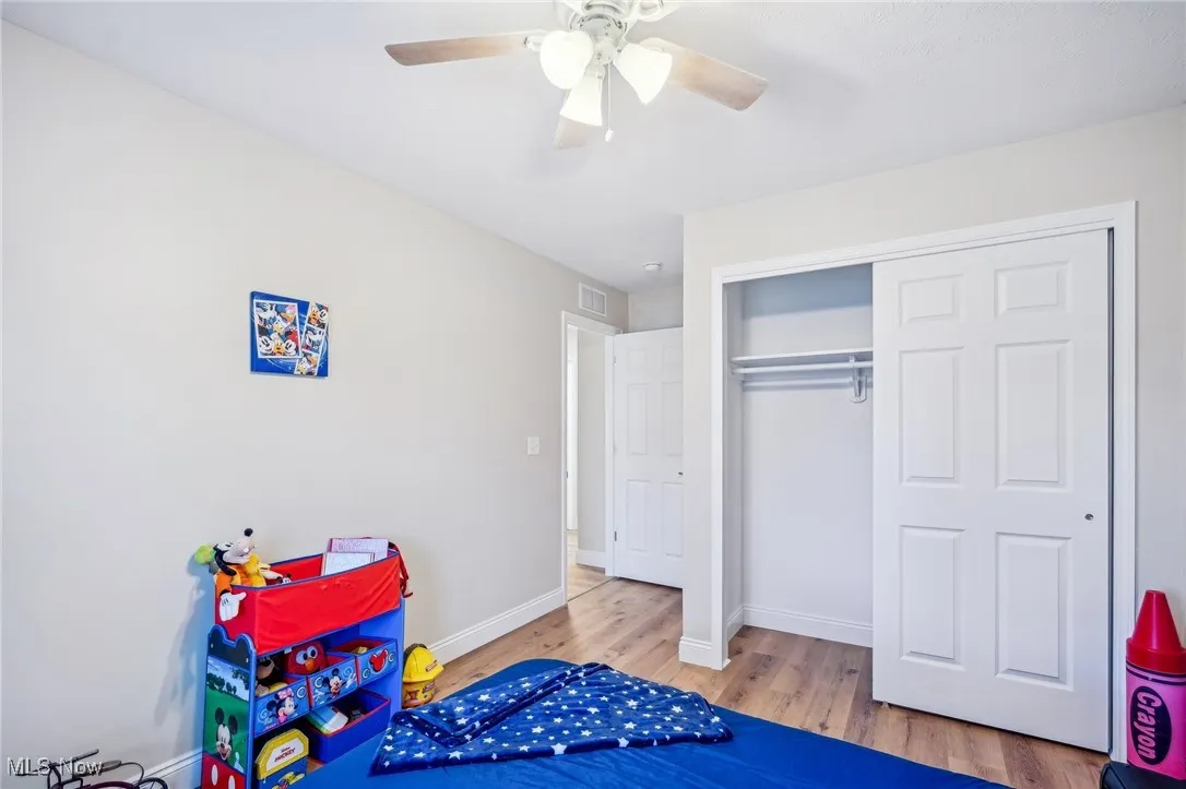 Playroom with ceiling fan, visible vents, baseboards, and wood finished floors