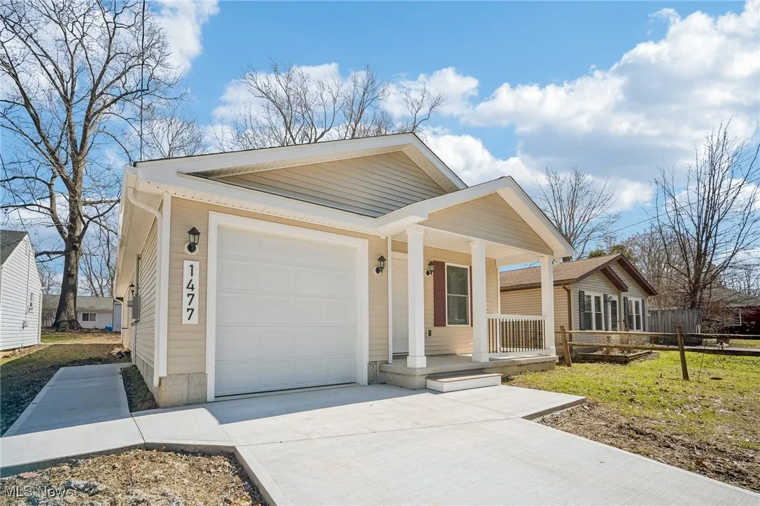 View of front facade featuring covered porch, concrete driveway, an attached garage, and fence