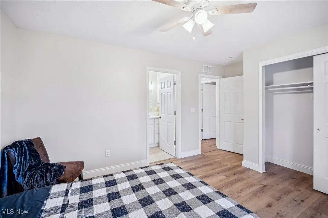 Bedroom featuring a ceiling fan, visible vents, baseboards, light wood-style floors, and a closet