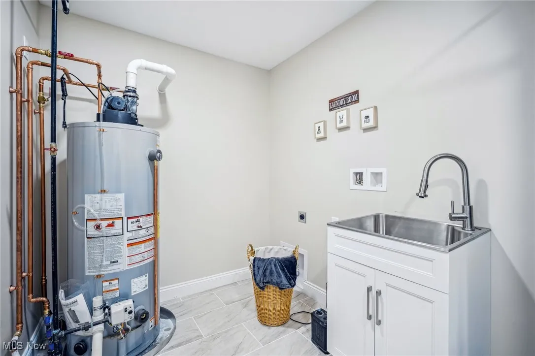 Clothes washing area featuring washer hookup, a sink, gas water heater, cabinet space, and hookup for an electric dryer
