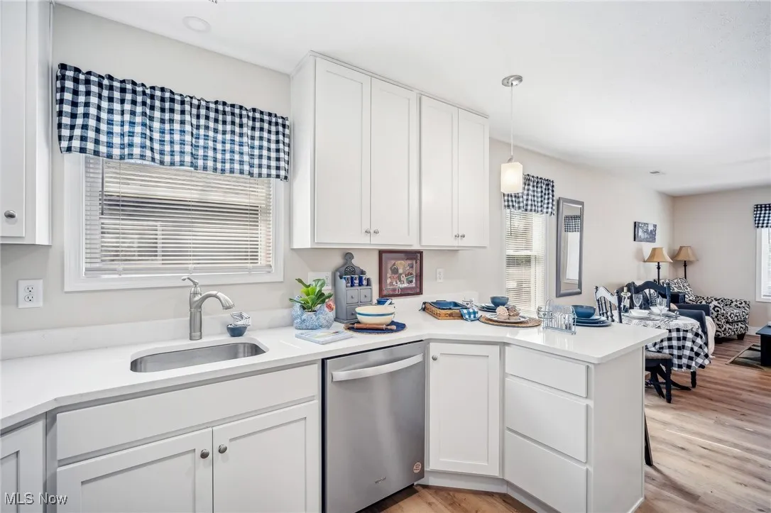 Kitchen featuring a sink, dishwasher, a peninsula, and white cabinets