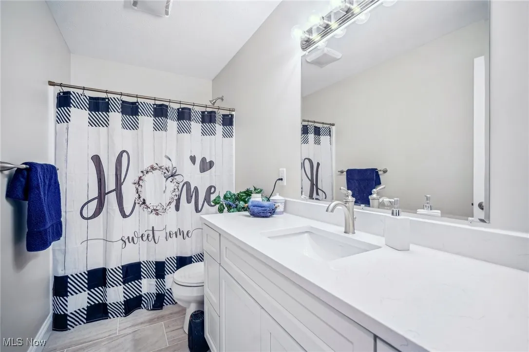Bathroom with vanity, curtained shower, and toilet