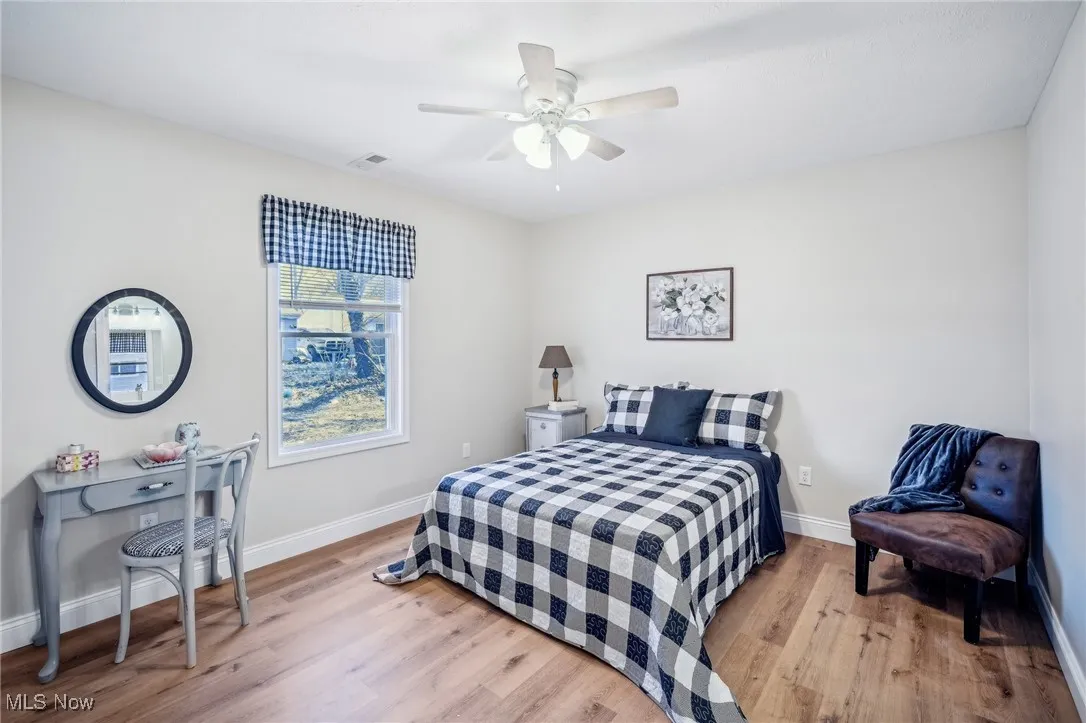 Bedroom with visible vents, a ceiling fan, baseboards, and wood finished floors