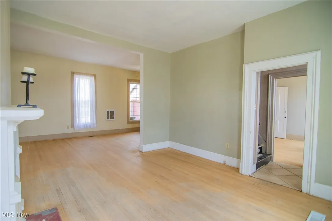 Unfurnished living room with light wood-type flooring, baseboards, and visible vents