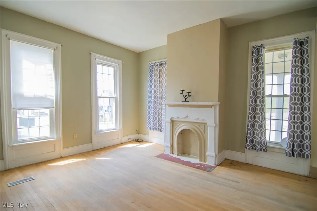 Unfurnished living room with visible vents, a wealth of natural light, and wood finished floors