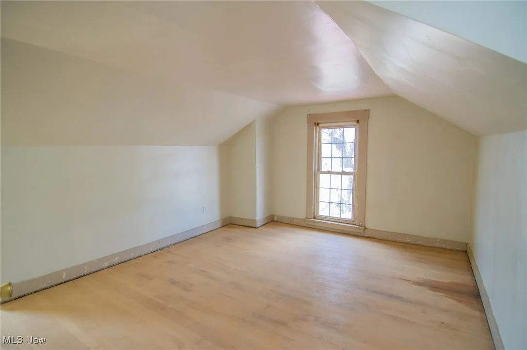 Additional living space featuring light wood-style floors, baseboards, and vaulted ceiling