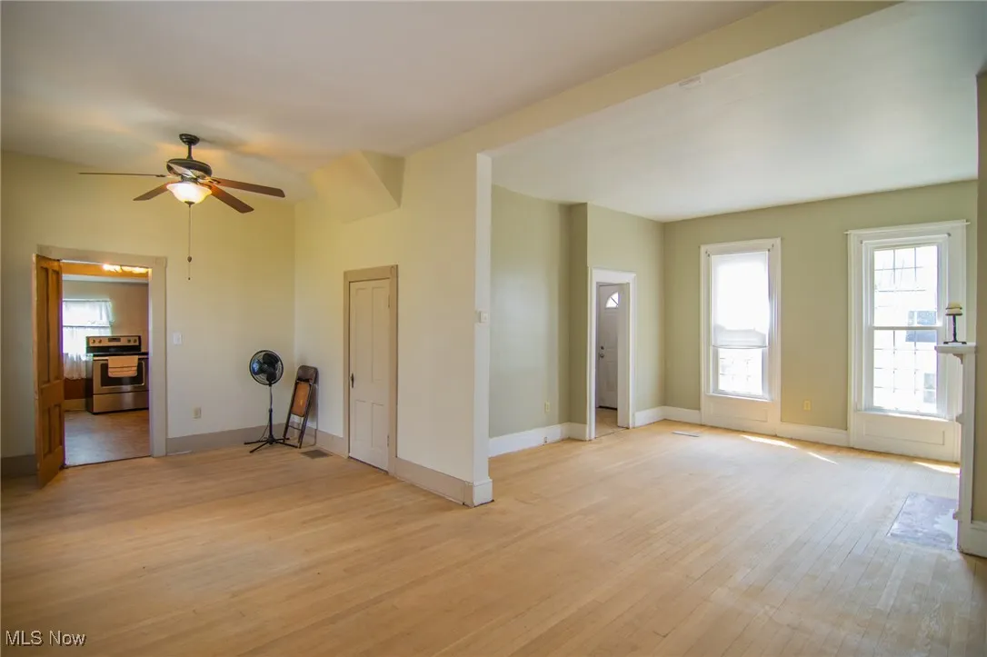 Spare room featuring light wood-style flooring, a ceiling fan, and baseboards