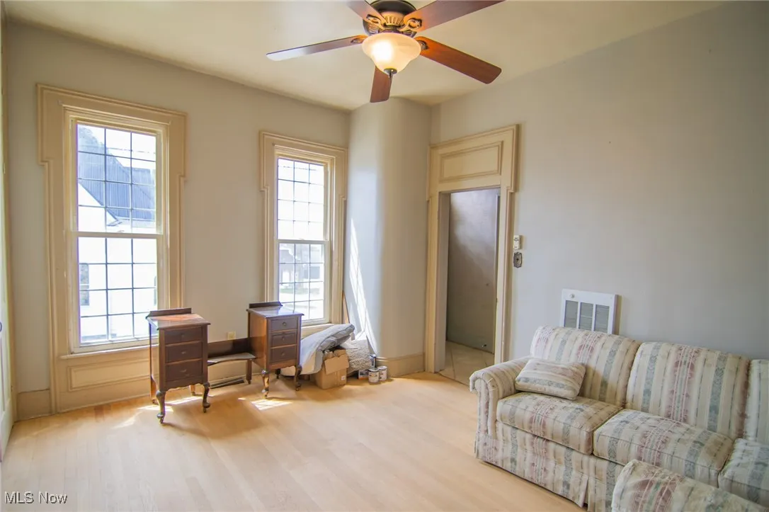 Living area with light wood-type flooring, ceiling fan, and visible vents