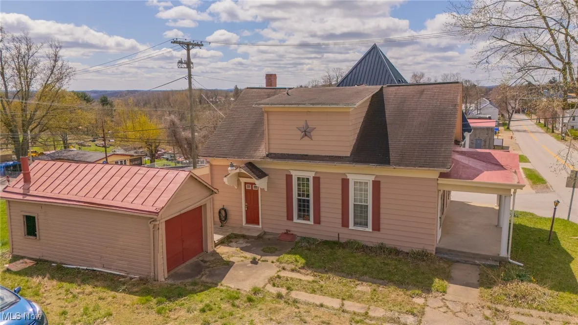View of front facade with an outdoor structure and a shingled roof
