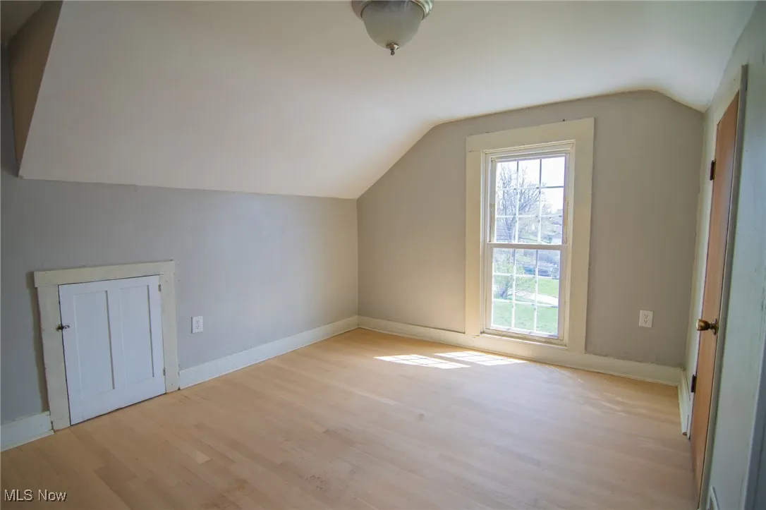 Additional living space featuring light wood-style flooring, vaulted ceiling, and baseboards