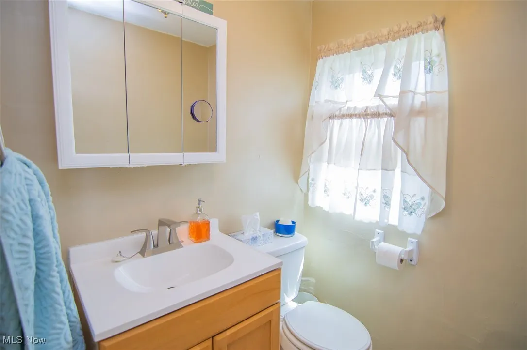 Half bath featuring toilet, a healthy amount of sunlight, and vanity
