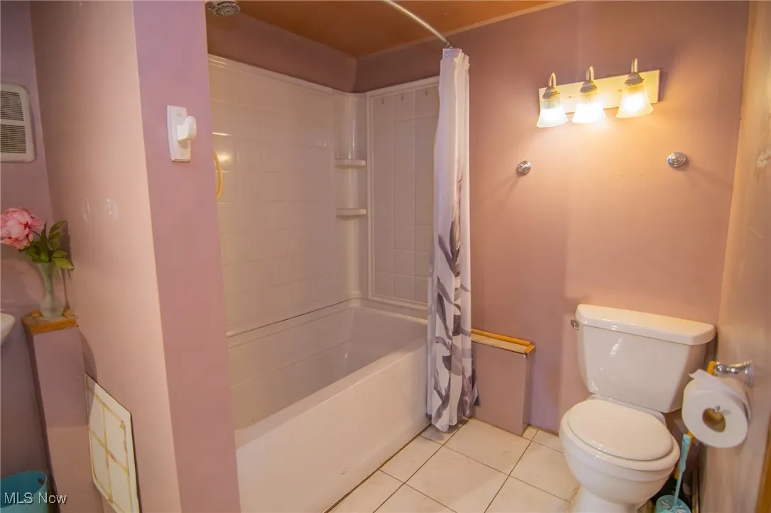 Full bathroom featuring shower / bath combo, tile patterned flooring, and toilet