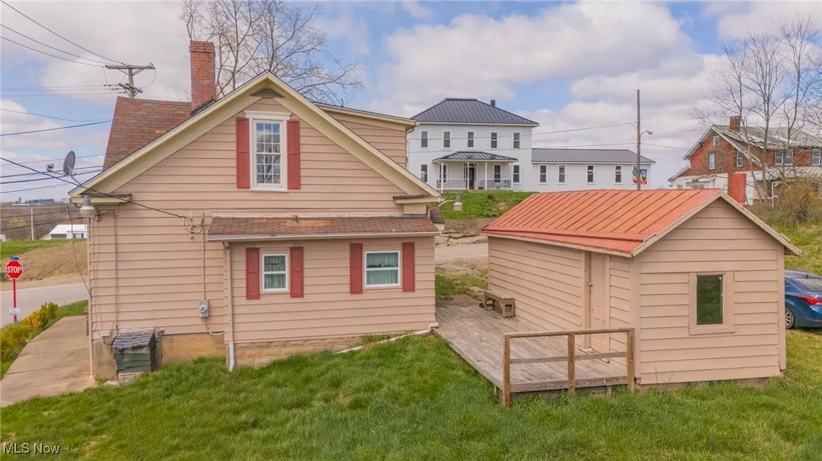 Back of property featuring a yard, a chimney, and an outbuilding