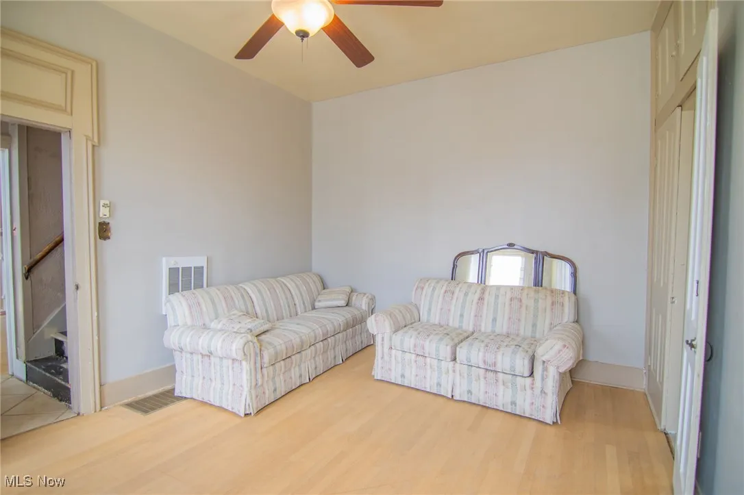 Living room featuring wood finished floors, baseboards, a ceiling fan, and visible vents