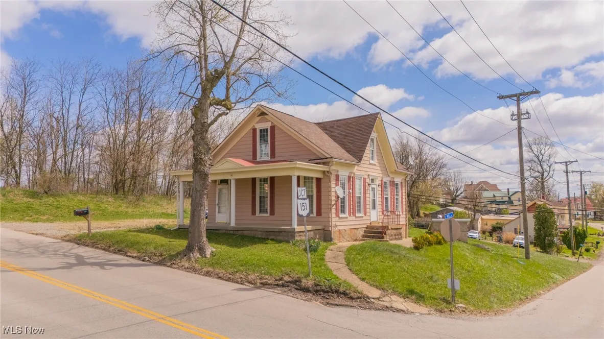 View of front facade with a front yard, a shingled roof, and covered porch
